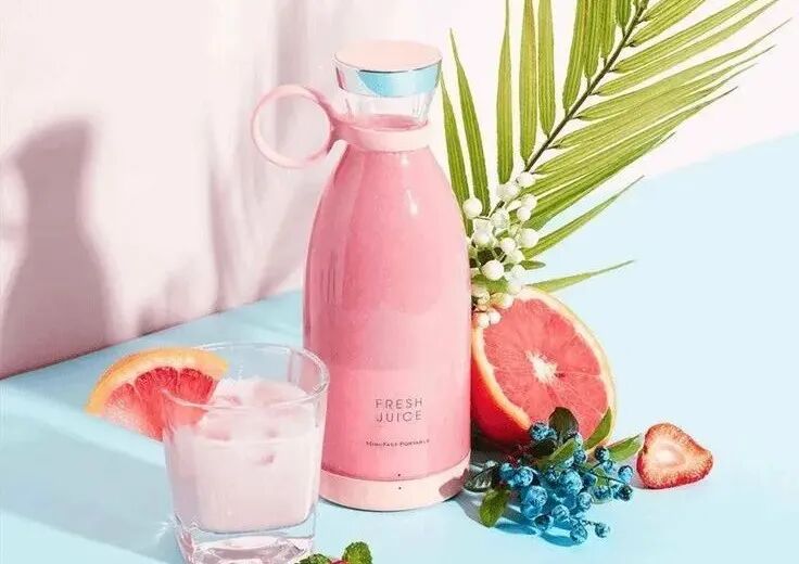 This may contain: a bottle of pink liquid next to some sliced grapefruits and strawberries