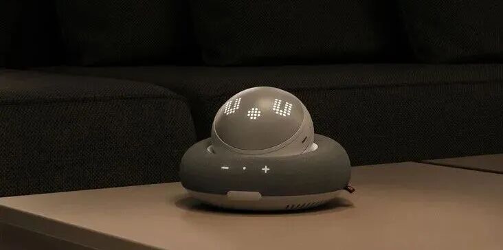 This may contain: an alarm clock sitting on top of a table next to a black couch in a living room